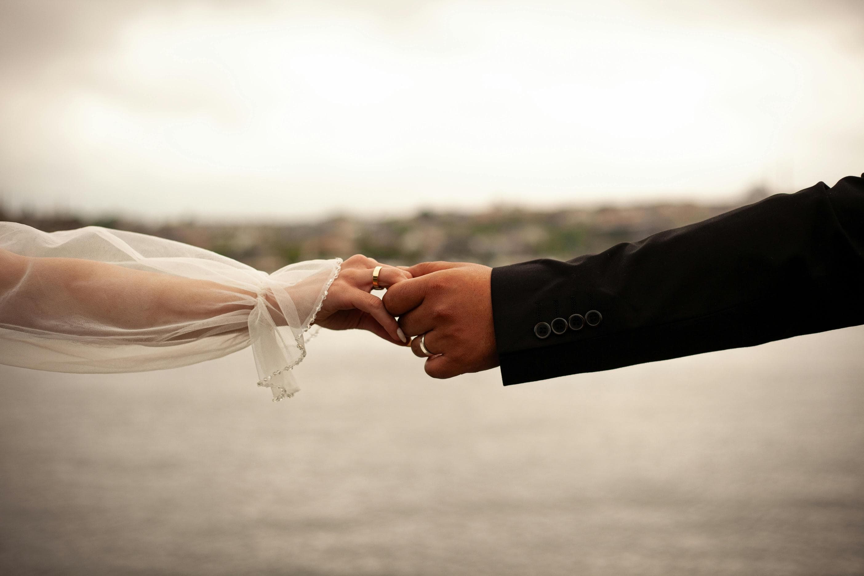 Bride and Groom holding hands with wedding rings, luxury wedding editorial